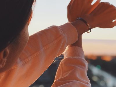 Person stretching arms towards the sky during sunrise